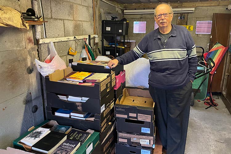 Ken Jeffery stands in his garage with boxes of donated books